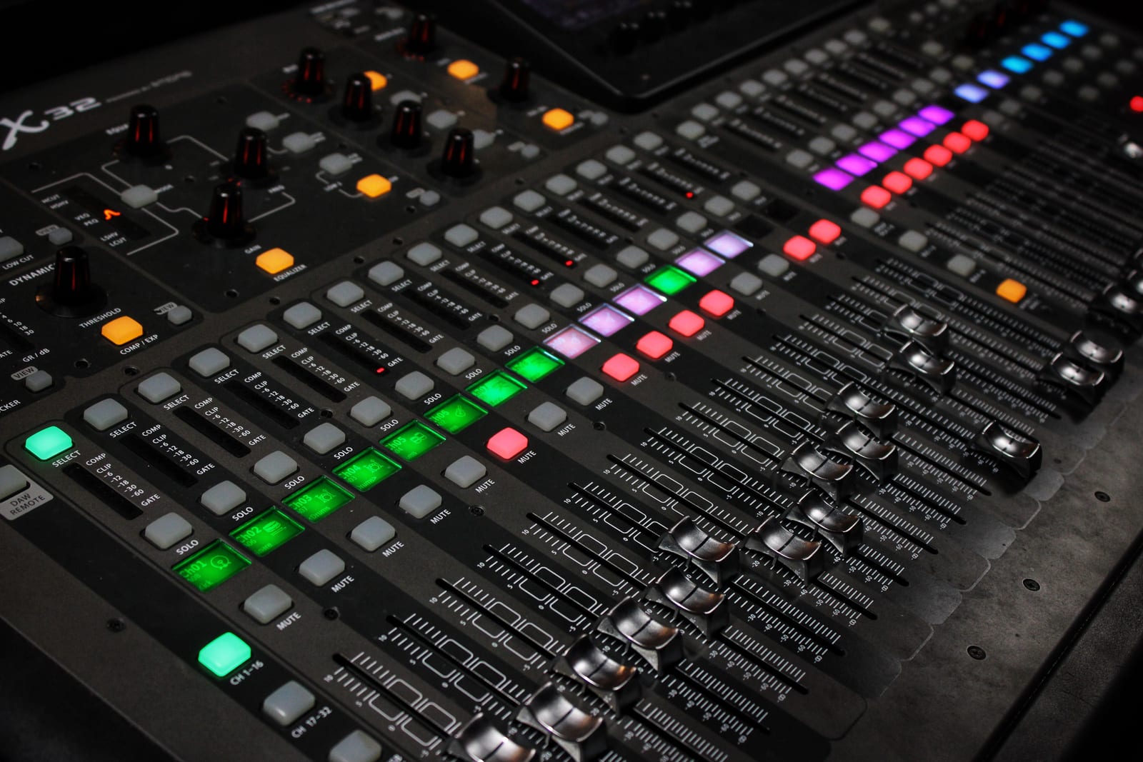 A broadcast mixing console with lit faders.